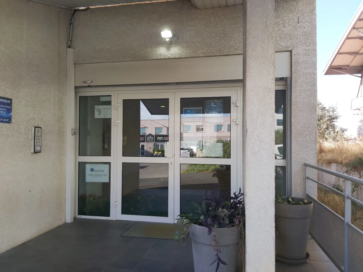 La porte vitrée du site, sous l'auvent : une plaque au nom de Pascale Ricciardi, marquée d'une empreinte de pied, est apposée sur le vantail de gauche.